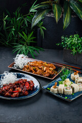 Asian dinner set of chicken with onion, celery, cashew nuts, pork in Thai sweet chili sauce and sushi roll set with shrimps tempura, cucumber, onion.