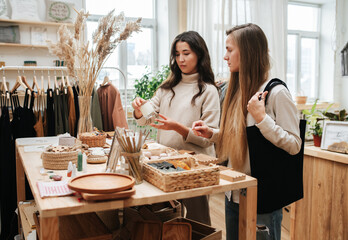 A sales consultant demonstrates handmade candles to a buyer in an eco store