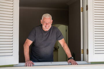 happy elderly man standing at home window