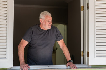 elderly man standing at home window