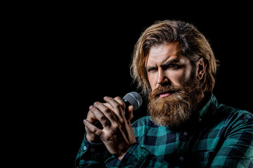 Male singing with a microphones. Man with a beard holding a microphone and singing. Bearded man in karaoke sings a song into a microphone. Bearded man singing with microphone