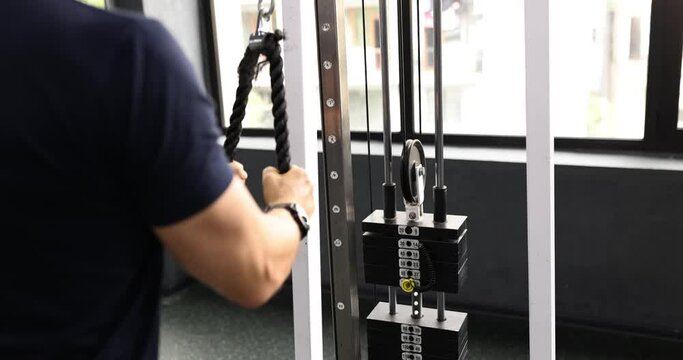Sportsman doing strength exercises on weight machine at fitness center. Man testing vitality during workout in resort gym slow motion