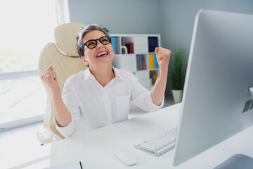 Photo of lucky impressed lady expert wear white shirt rising fists successful startup modern device...