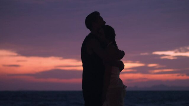 Man in love tenderly hugs his girlfriend at sunset on sea. Couple in love concept. Romantic couple sharing beautiful moment on beach sunset date. Man and woman in love enjoying evening at sea together