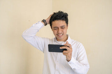 Indonesian office employee wear white clothes unhappy playing game when working hour. The photo is suitable to use for man expression advertising and fashion life style.