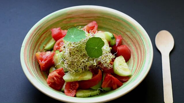 Serving vegetable salad in a restaurant. Vegetable salad of tomatoes, cucumbers and alfalfa sprouts decorated with nasturtium leaves.  The idea of serving a vegetable salad for a restaurant. 