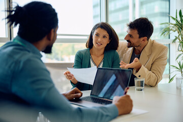 Mid adult couple having meeting with their insurance agent in office.