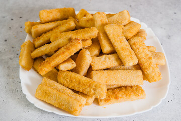 Crunchy breaded fish sticks made from wild caught Alaskan Pollock close-up on white plate