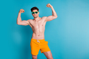 Photo portrait of handsome young guy raise fists flexing muscles wear trendy yellow shorts isolated...