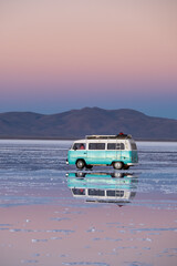 Perfect reflection of a classic van on a salt flat with water at sunset