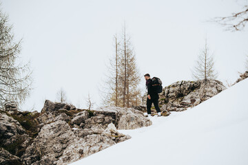 Hombre haciendo senderismo con mochila en la montaña con nieve , en Dolomitas , Alpes italianos 