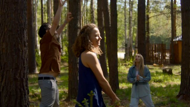 People have fun playing volleyball in park. Stock footage. Friends are actively playing volleyball in forest clearing. Fun ball games for group of friends in forest