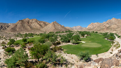 Golf greens nestled among dramatic mountains