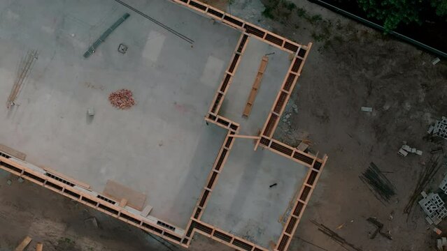 Aerial top down view of commercial construction site, concrete truck mixers dump cement mixture to pour floor 