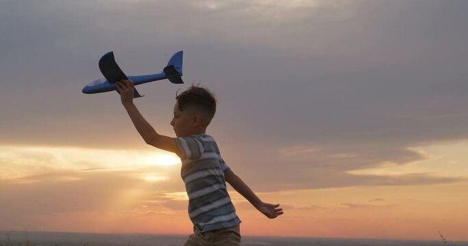 Kid boy run with toy airplane at sunset. Toddler kid play have fun outdoors. Happy childhood concept
