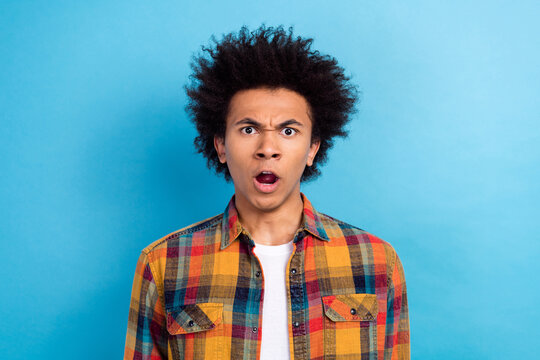 Photo of astosnished disappointed guy with afro hairdo wear plaid jacket sceaming open mouth argue isolated on blue color background