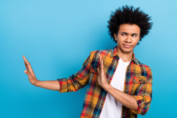 Photo of moody unhappy guy wear plaid shirt showing arms dislike empty space isolated blue color...