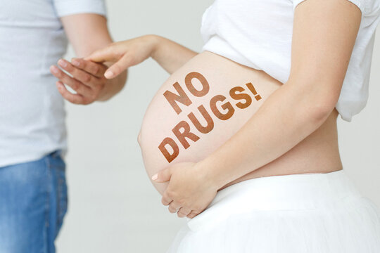 A pregnant woman holds her husband's hand on her stomach with the inscription - No Drugs, a exclamation point.