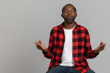 Relaxed black bearded man wearing red checkered shirt practicing yoga