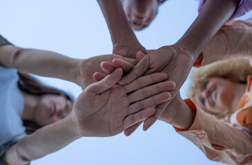 Diverse team joining hands. Mixed race group of young people in circle and putting hands together,...