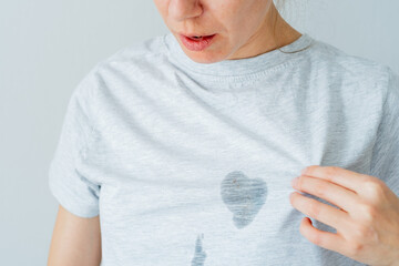 Unrecognized surprised female showing at dirty grease stain on a gray t-shirt. daily life stain...