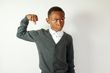 Portrait of funny black male school kid in gray cardigan and formal shirt making faces pretending...