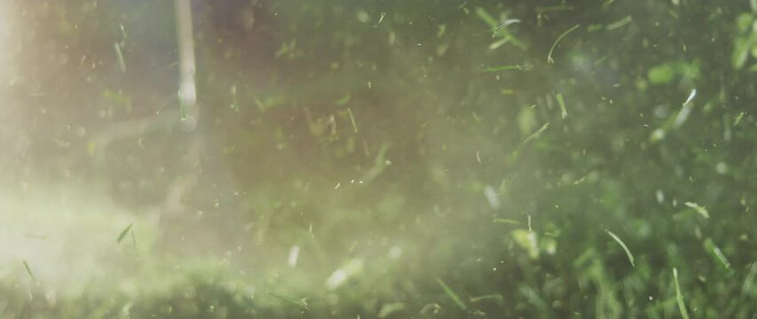 Mowing grass with an electrical trimmer close-up in summer day, slow-motion. Farmer mowing grass with brush cutter
