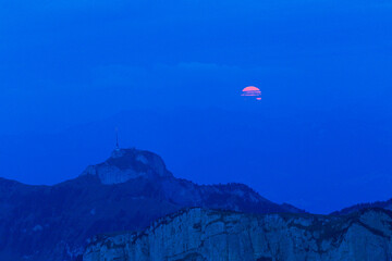 Fototapeta na wymiar The full red moon rising over the Swiss Alpstein viewed from Schaefler with the summit of Hoherkasten at the background