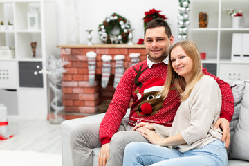 a couple sits on a sofa in a room decorated with Christmas ornaments