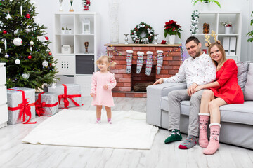 Obraz na płótnie Canvas A little girl with her parents prepare for the Christmas holidays