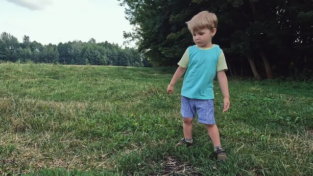 A little laughing boy dances in nature. High-quality shooting in 4K format. Hobby concepts, joy, fun, music, entertainment, good mood, party, relaxation, exercise, skill, physical activity, melodies