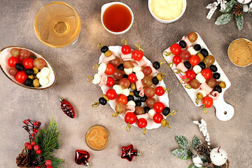 Christmas and New Year's dishes, a set of snacks and refreshing drinks for the festive table. A plate with canapes of tomatoes, mozzarella cheese, olives, black olives and grapes on a marble table,