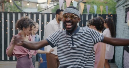 Portrait of sad African American man standing then dancing having fun at open air party in cafe. Mood change and entertainment concept.
