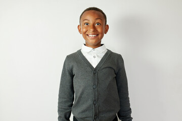 Overjoyed crazy smiling cheerful african american little boy in cardigan standing still like doll against white copy space background, astonished with good news, receiving high mark for test