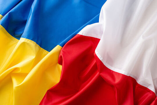 Nations united: wavy Ukrainian and Polish flags stand together in top view photo, symbolizing their shared values
