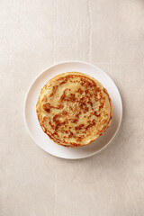 Crepes, thin pancakes with honey on a white plate. Marble background. Top view.