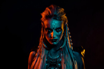 Portrait of dangerous fearless viking woman evil glance blue orange light effect isolated on black background