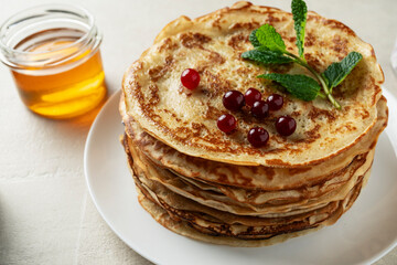 Large pancakes on a light stone background are served by a female cook, top view, home cooking, Maslenitsa, Easter