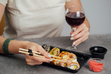 Close-up of hands holding sushi roll with chopsticks. 