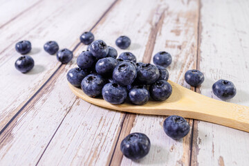 Fresh sweet blueberry fruit in wooden spoon. Dessert healthy food. Group of ripe blue juicy organic berries.
