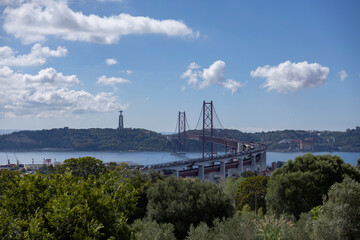 View of the 25 of April Bridge (Ponte 25 de Abril) and the a statue of Jesus Christ in the city of Lisbon in Portugal.