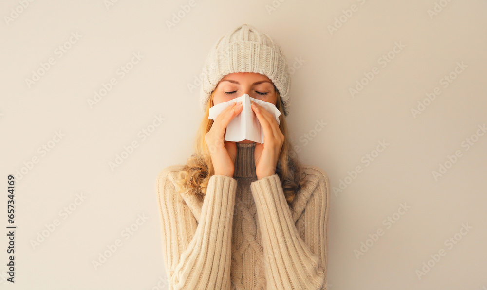 Wall mural sick upset woman sneezing blow nose using tissue wearing warm soft knitted clothes, hat and sweater 