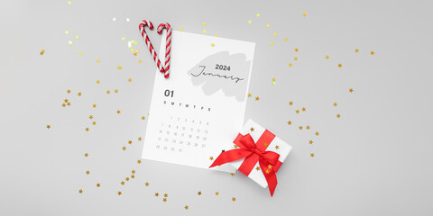 Paper calendar for January 2024 with gift box and candy canes on grey background