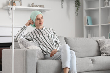 Teenage girl after chemotherapy sitting on sofa at home