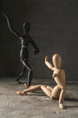 Wooden mannequins on table against dark background. Domestic violence concept