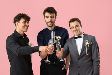 Young men dressed for prom with glasses of champagne on pink background © Pixel-Shot