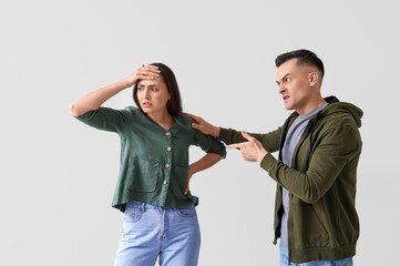 Young couple quarreling on light background
