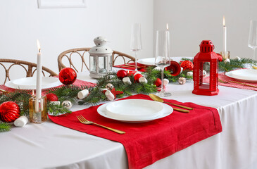 Festive table setting with clean plates, cutlery and Christmas decorations