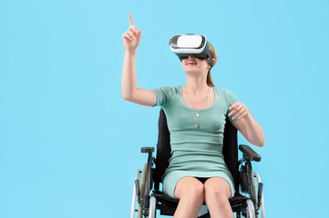 Young woman in wheelchair using VR glasses on blue background