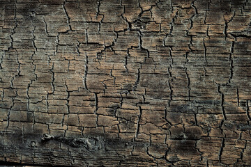 Texture of the cracked flat surface of dark сharred wood. Burnt wooden board.v